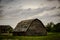 Creepy, old and aged abandoned wooden house in a field under the cloudy and rainy sky