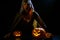A creepy sorceress in a cloak casts a spell on pumpkins for Halloween