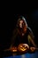 A creepy sorceress in a cloak casts a spell on pumpkins for Halloween