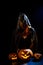 A creepy sorceress in a cloak casts a spell on pumpkins for Halloween