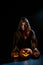 A creepy sorceress in a cloak casts a spell on pumpkins for Halloween