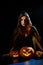 A creepy sorceress in a cloak casts a spell on pumpkins for Halloween