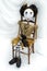 Creepy steampunk doll sitting on wooden chair. Vertical.