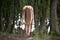 Creepy woman with long hair standing bent down in moody dark forest