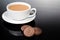 Creme-filled sandwich cookie and milk coffee on dark reflective background