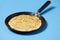 Crepe closeup, thin pancake on a frying pan, blue background