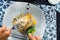 Crepe covered in white sauce lying on plate with broccoli pieces, as seen from above, persons point of view, classy