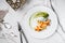 Crepes with filet salmon and cheese, red fish caviar and green sauce on white plate over marble background.