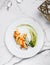Crepes with filet salmon and cheese, red fish caviar and green sauce on white plate over marble background.