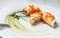 Crepes with filet salmon and cheese, red fish caviar and green sauce on white plate over marble background