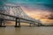 The Crescent City Connection bridge over the Mississippi River with lush green trees, plant and grass and powerful clouds