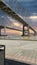 The Crescent City Connection bridge over the Mississippi River with lush green trees and plants and powerful clouds at sunset