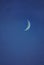 Crescent moon on the night sky seen trough clouds