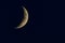 Crescent moon on the night sky seen trough clouds