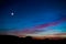 Crescent moon over the sunset sky in the mountains