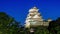 Crescent moon sets over Himeji Castle as lights come on in early evening