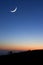 A crescent moon at sunset above