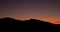 Crescent moon and sunset over silhouette of desert ridge on fall evening