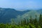 Crest of the mountain range with stone placers covered with green lichens and slopes with spruce forest in Carpathian Mountains at