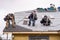 Crew Installing New Shingles on Roof on a Rainy Day