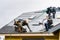 Crew Installing New Shingles on Roof on a Rainy Day