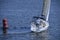 Crew of yachtsmen conducting a flanking manoeuvre, sailing yacht passing by the river beacon