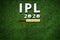 Cricket bat and leather ball resting on a cricket bat with ipl 2020 text placed on green grass cricket ground pitch,ipl 2020 india