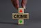 Crime rate symbol. Businessman holds a wooden cubes with up arrow. Wooden block with the concept word Crime. Beautiful grey table