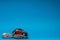 Crimson car figurine on top of a boulders, on blue background