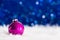 Crimson Christmas ball on white fur with garland lights on blue