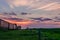 Crimson cloudy sky at sunset of the day over green grass, grain