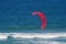 CRIMSON KITE SURFER SAIL ALOFT ABOVE THE OCEAN WITH WHITE SURF OFF THE COAST AT UMHLANGA ROCKS, KWA-ZULU NATAL, SOUTH AFRICA