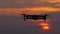 Crimson sunset, a copter flies on its background and disappears in the distance