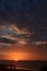 Crimson Tropical sunrise seascape with pink tinged dark nimbostratus cloud. Huay Yang, Thailand