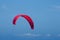 CRIMSON WIND SURFER SAIL ALOFT AGAINST BLUE SKY OFF THE COAST AT UMHLANGA ROCKS, KWA-ZULU NATAL, SOUTH AFRICA