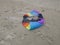 Crinkled kite in rainbowcolors with white threads laying on the beach of Velsen Netherlands