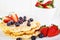 Crisp golden fresh baked waffle topped with strawberries and blueberry