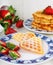 Crisp golden fresh baked waffle topped with strawberries on whit