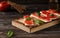 Crispbread with feta cheese, red tomatoes and mini spinach leaves, on a wooden board