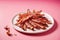 Crispy bacon strips on a plate, pink background
