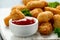 Crispy Battered scampi nuggets with ketchup on white wooden board