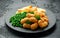 Crispy Battered scampi nuggets served on slate plate with potato chips and green peas