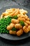 Crispy Battered scampi nuggets served on slate plate with potato chips and green peas