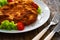 Crispy breaded fried pork chop and fresh vegetables on wooden table