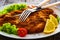 Crispy breaded fried pork chop and fresh vegetables on wooden table