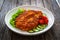 Crispy breaded fried pork chop and fresh vegetables on wooden table