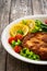 Crispy breaded fried pork chop, green asparagus and fresh vegetables on wooden table