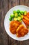 Crispy breaded fried pork loin chops with sweet potato fries and boiled Brussels sprouts on wooden table