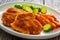 Crispy breaded fried pork loin chops with sweet potato fries and boiled Brussels sprouts on wooden table