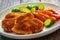 Crispy breaded fried pork loin chops with sweet potato fries and boiled Brussels sprouts on wooden table